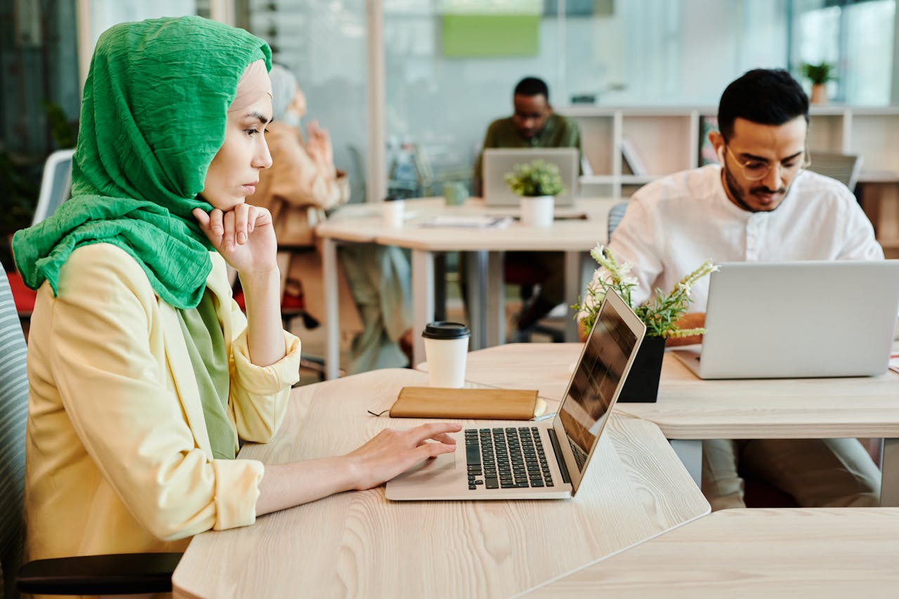 Diverse team working in a modern office with laptops, focusing on collaboration and productivity.